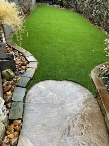 Artificial Grass In A Garden, Complemented By A Stone Walkway